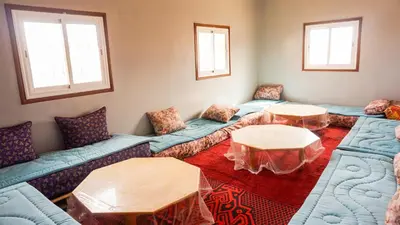 a living room with blue couches and two tables at Ouarzazate Youth Hostel YHO in Ouarzazate