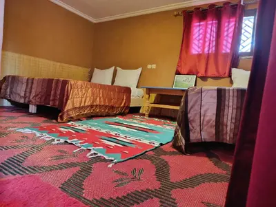 a room with two beds and a rug on the floor at Bivouac Lot Of Stars in Ouarzazate