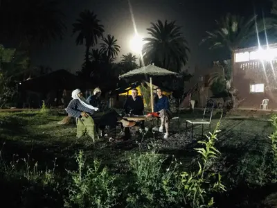 a group of people sitting at a table at night at Bivouac Lot Of Stars in Ouarzazate
