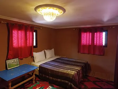a bedroom with a bed and red curtains and a chandelier at Bivouac Lot Of Stars in Ouarzazate