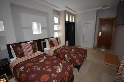 a hotel room with two beds and a hallway at Hôtel-Café-Restaurant Pyramides, in Taza