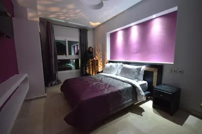 a person standing in a bedroom with a large pink wall at Hôtel-Café-Restaurant Pyramides, in Taza