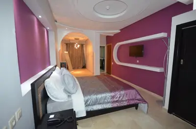 a bedroom with a purple wall with a bed and a tv at Hôtel-Café-Restaurant Pyramides, in Taza