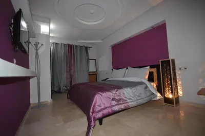 a bedroom with a bed with a purple wall at Hôtel-Café-Restaurant Pyramides, in Taza