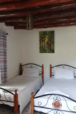 two beds in a bedroom with a painting on the wall at Relais De Tahla in Ain Boumahdi