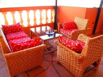 a room with wicker chairs and a table with red pillows at Riad Al Anwar in Tinerhir