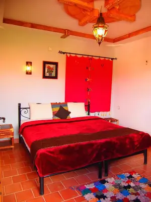 a bedroom with a red bed with a red window at Riad Al Anwar in Tinerhir
