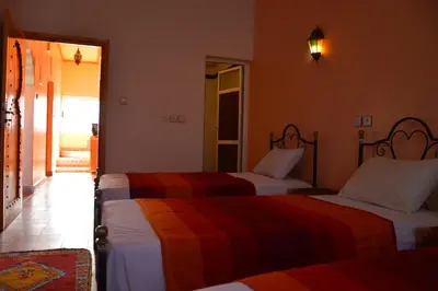 a hotel room with two beds and a mirror at Riad Al Anwar in Tinerhir
