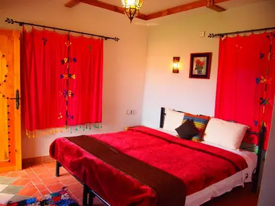 a bedroom with red curtains and a large bed at Riad Al Anwar in Tinerhir