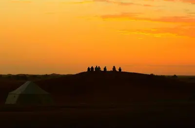 a group of people standing on top of a hill at sunset at Dar Azawad Royal Desert Camp - Erg Chigaga Luxury Glamping in Mhamid