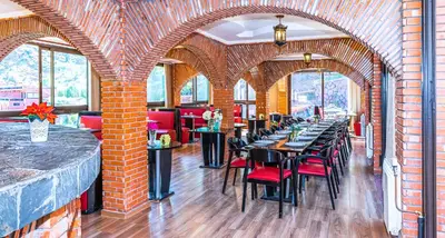 a restaurant with tables and chairs in a brick wall at Aurocher Marrakech Ourika Oukaimeden in Oukkainrdem