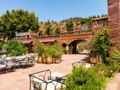 an outdoor patio with tables and chairs and a bridge at Aurocher Marrakech Ourika Oukaimeden in Oukkainrdem