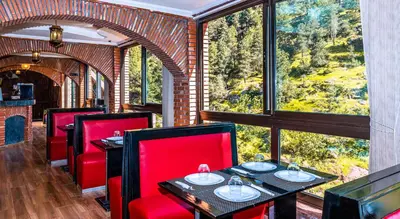 a restaurant with red chairs and tables and a large window at Aurocher Marrakech Ourika Oukaimeden in Oukkainrdem
