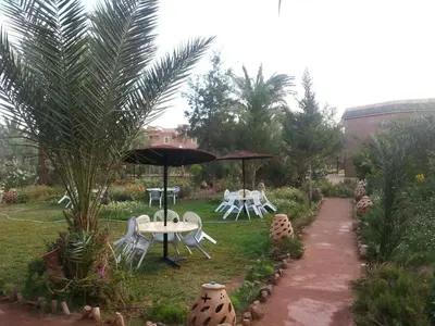 a garden with a table and chairs and an umbrella at d'hôte Jnane-Dar Diafa in Tamegroute
