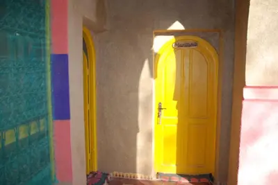 a yellow door in a room with a wall at d'hôte Jnane-Dar Diafa in Tamegroute