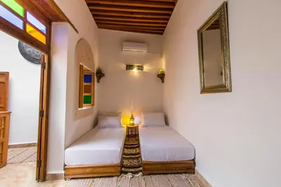 two beds in a room with a mirror and a lamp at Dar Bhija in Fès
