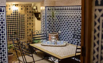 a table and chairs in a room with blue and white tiles at Dar Bhija in Fès