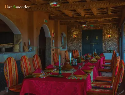 a long table in a room with red tables and chairs at Dar Amoudou in Ouarzazate