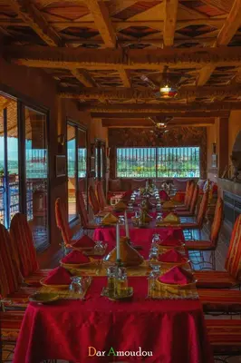 a dining room with a long table with red table cloth at Dar Amoudou in Ouarzazate