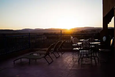 a patio with a table and chairs and the sunset at Dar Amoudou in Ouarzazate