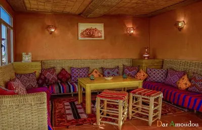 a room with a couch and a table and chairs at Dar Amoudou in Ouarzazate