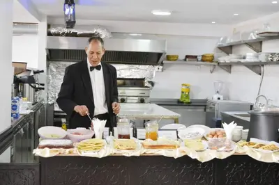 a man in a kitchen preparing food on a table at Rose Valley Hotel in Ouarzazate