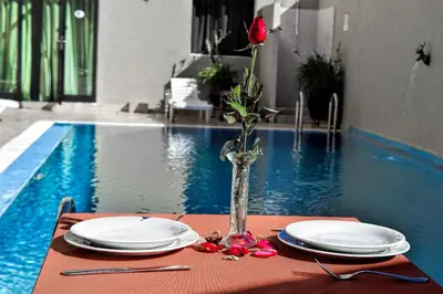 a table with plates and a vase with a rose at Rose Valley Hotel in Ouarzazate