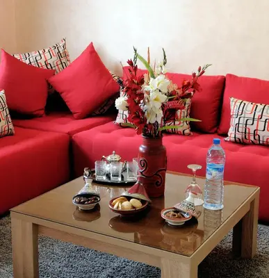 a living room with a red couch and a coffee table at Aparthotel Les Oliviers Suites & Spa in Fès