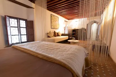 a bedroom with a large bed and a living room at Riad El Ma in Meknès
