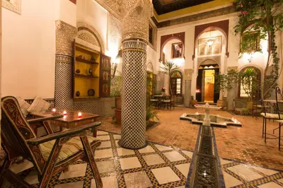 a large room with columns and tables and chairs at Riad El Ma in Meknès