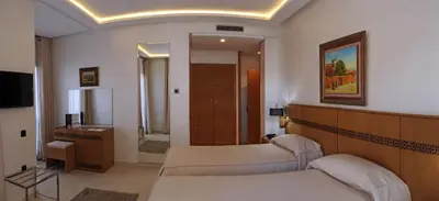 a hotel room with two beds and a bathroom at Hôtel l'escale in Fès