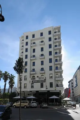 a tall white building with cars parked in front of it at Hôtel l'escale in Fès
