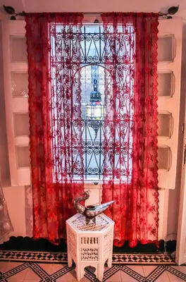 a window with a red curtain and a table at Riad Dar Arsama in Fès