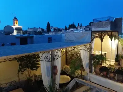 a balcony with a view of a city at night at Riad Dar Arsama in Fès