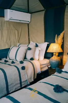a bedroom with two beds and a lamp at Luxury Camp Chebbi in Merzouga