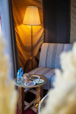 a table with two plates of food and a lamp at Luxury Camp Chebbi in Merzouga