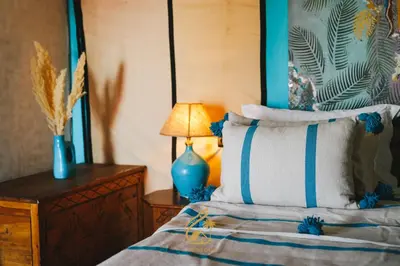 a bedroom with a bed with a blue lamp on a table at Luxury Camp Chebbi in Merzouga