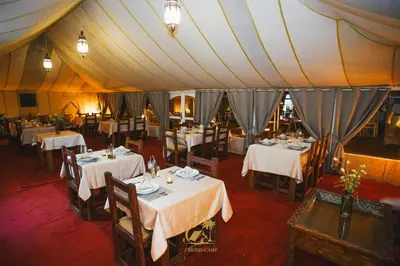 a dining room with tables and chairs in a tent at Luxury Camp Chebbi in Merzouga