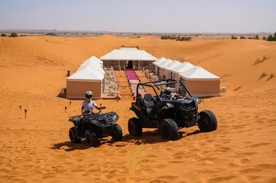 two people on atvs in the sand in the desert at Luxury Camp Chebbi in Merzouga