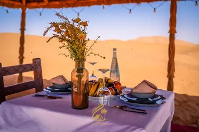 a table with a vase with flowers in the desert at Luxury Camp Chebbi in Merzouga