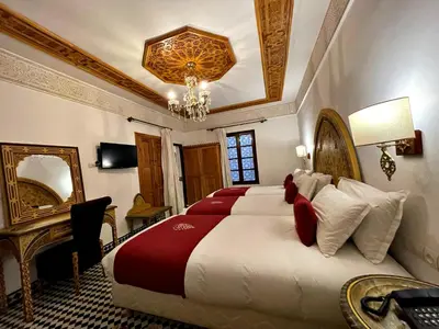 a bedroom with a large bed and a chandelier at Riad Marjana suites & Spa in Fès