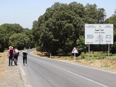 two people walking down a road with a sign at Le Gite du Barrage in Zaouia Ben Smine
