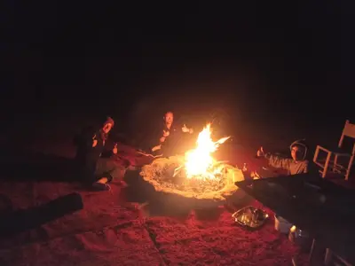a group of people sitting around a fire at night at Bivouac Les Nomades & Foum zguid camel trekking and tours in Foum Zguid