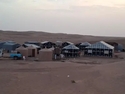 a group of huts in the middle of the desert at Bivouac Les Nomades & Foum zguid camel trekking and tours in Foum Zguid