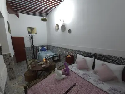 a living room with a bed and a table with a table at Dar Enouiina in Fès