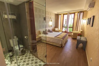 a bedroom with a bed and a glass shower at Ksar Sultan Dades - Dades Valley Retreat in Boumalne