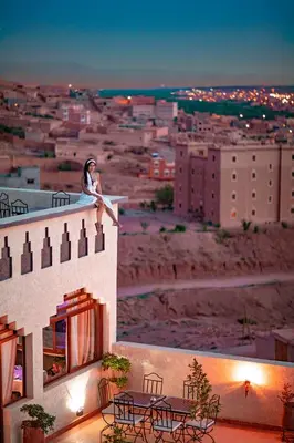 a woman sitting on the ledge of a building at Ksar Sultan Dades - Dades Valley Retreat in Boumalne