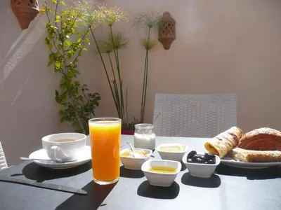 a table with a plate of food and a glass of orange juice at Dar Le 44 in Fès