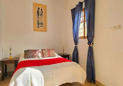 a bedroom with a bed and a window with blue curtains at Dar Le 44 in Fès