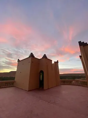 a building on a roof with a sunset in the background at Maison D'hotes Sahara in Aoufous